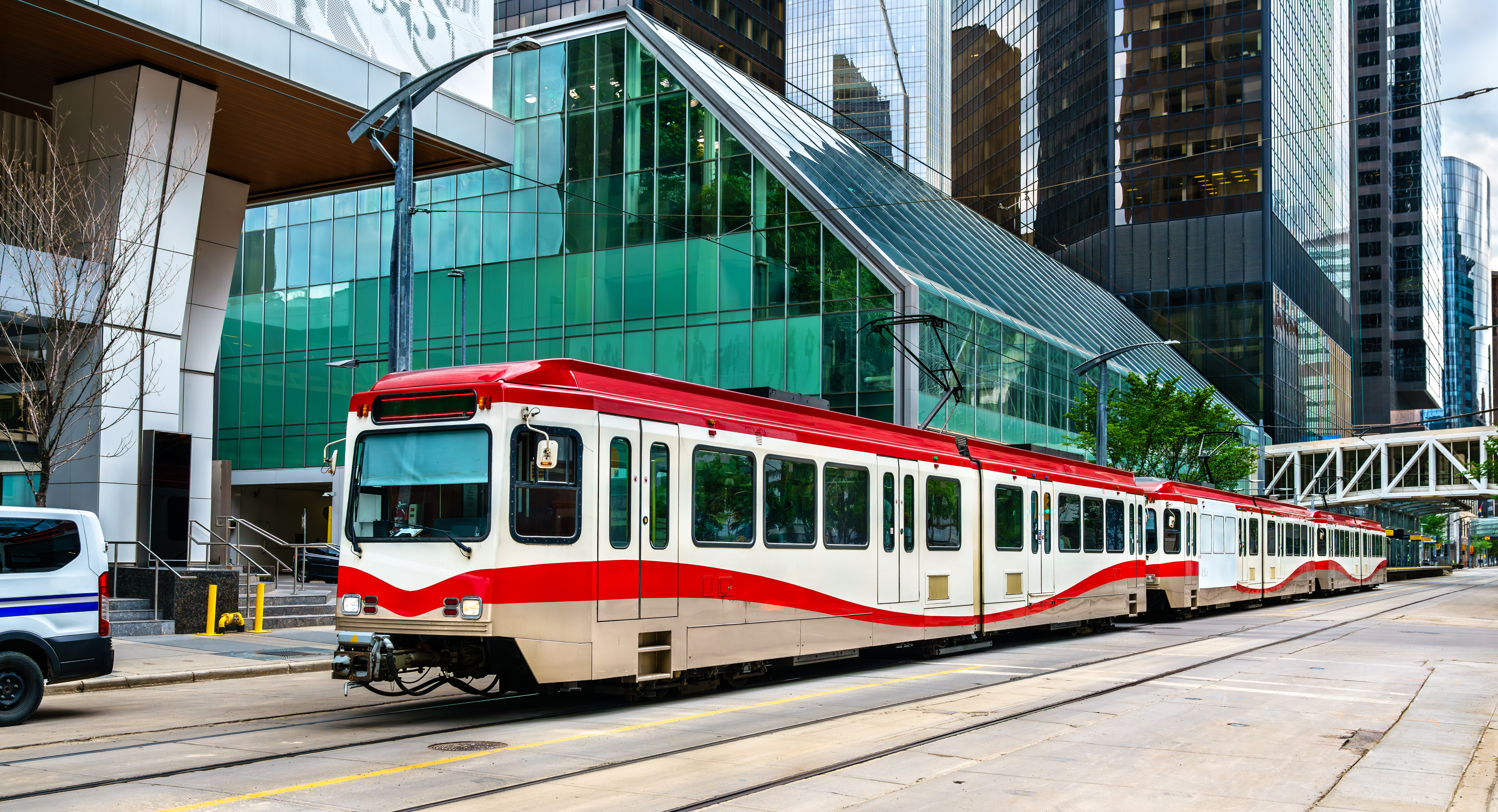 Un wagon rouge et blanc de CTrain glisse sur une voie de métro léger en plein centre-ville de Calgary.