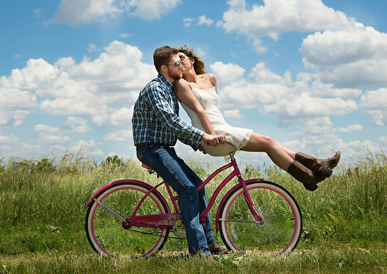 A man rides a bike while a woman rides the handlebars 
