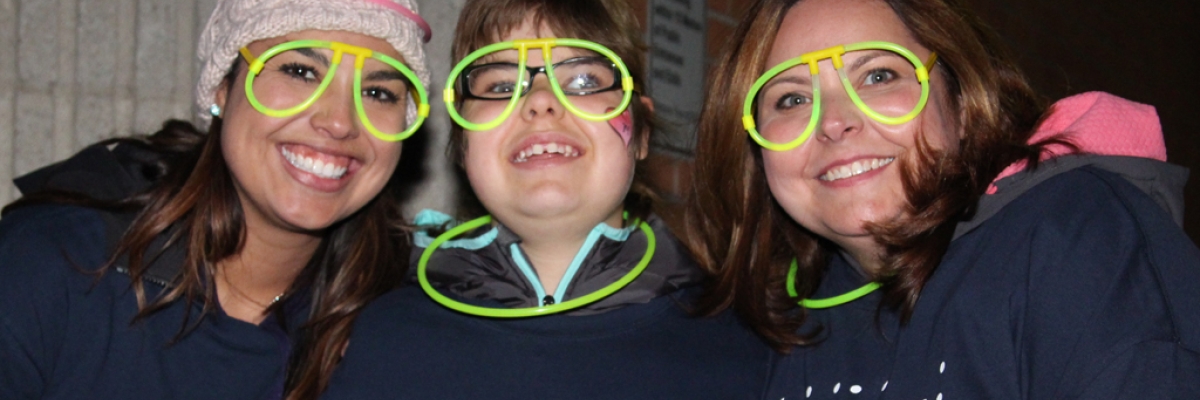 Trois participants à Marchons le soir portant des lunettes lumineuses tout sourire.