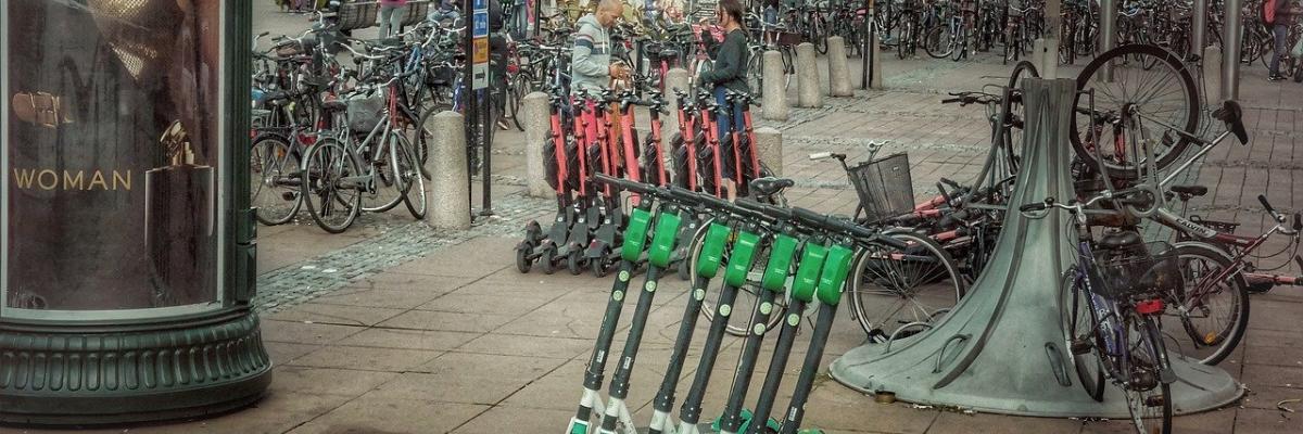 Un trottoir de la ville avec une rangée de scooters électriques alignés dessus.