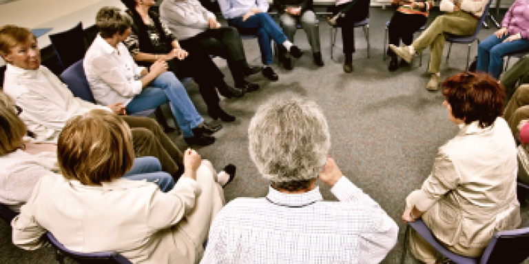 A large group of 17 people gather in a support group. They are seated in a circle.