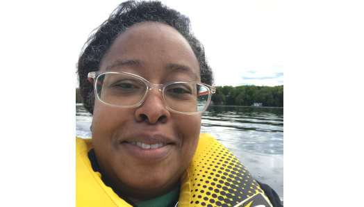 Llonella wears a yellow lifejacket and sits on a boat at CNIB Lake Joe.
