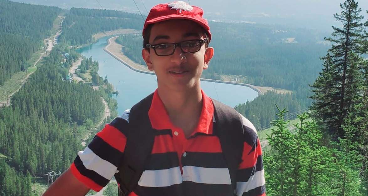 Un jeune homme pose pour une photo devant des montagnes pittoresques. 