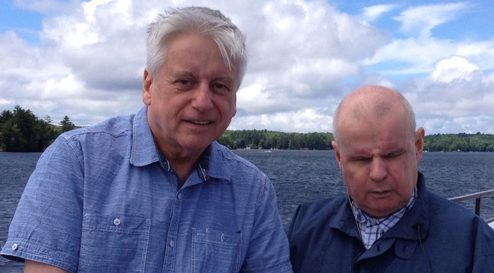 Rob Froom (à gauche) debout au bord du lac Joe avec son frère David. Rob tient la main de son frère.