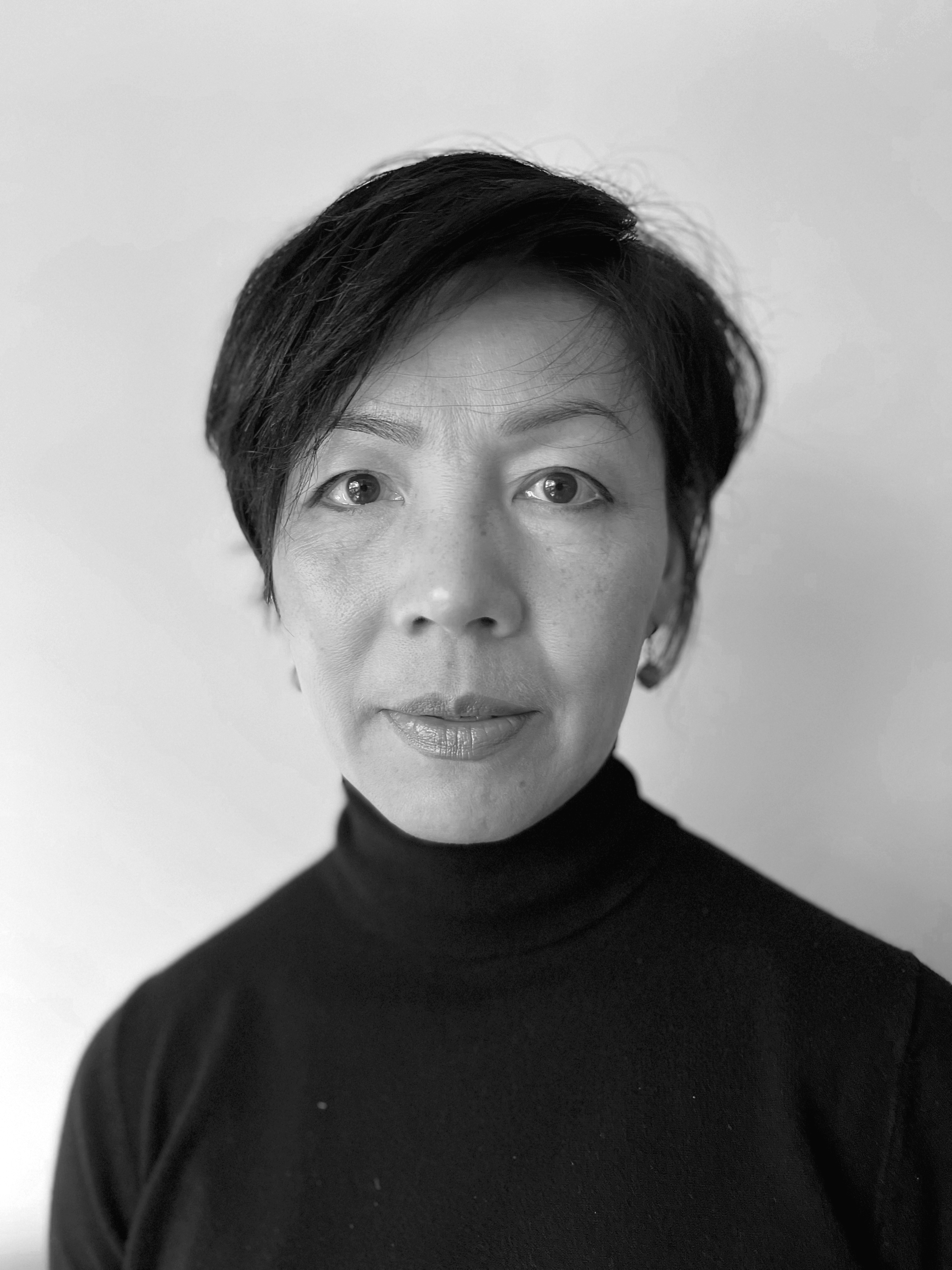 Portrait professionnel en noir et blanc de Nancy Vo. Nancy porte un col roulé noir, a des cheveux courts, noirs et elle apparaît calme et neutre.