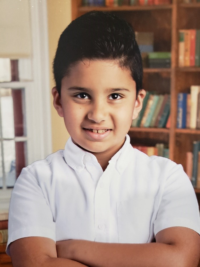 Ali Zaben, 9, poses for a school picture. He's smiling and crossing his arms. 