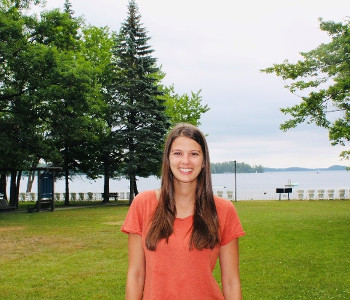 Ally standing on the grounds at Lake Joe, smiling with the water behind her.