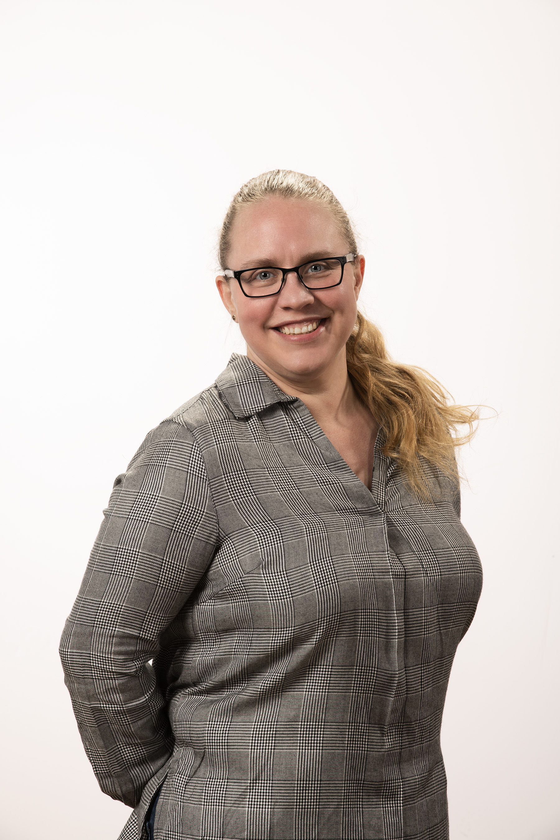 A professional headshot of Chantelle Painter. She is wearing glasses and business casual attire. She smiles while standing against a white background