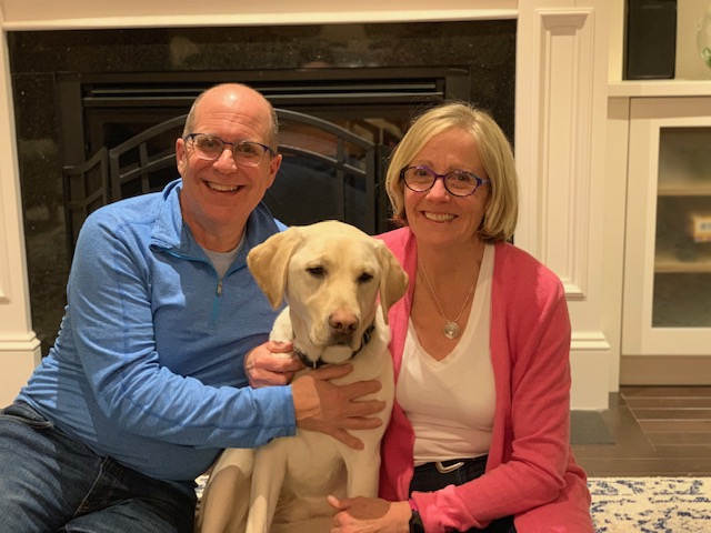 Un labrador blond assis sur le sol entre Patti Sullivan et son mari Patrick. 