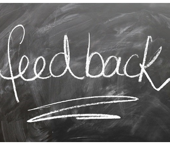 A dirty chalkboard with white text written in chalk on it. Text "Feedback." 