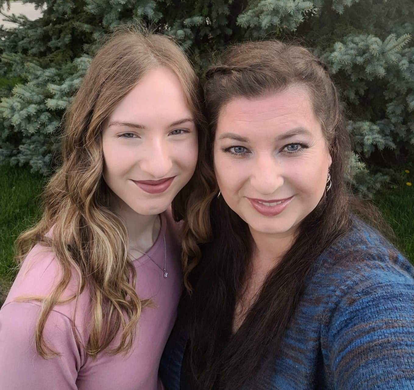 Emma (left) and Michelle (right) smile and pose for a photo in front of a beautiful green tree.