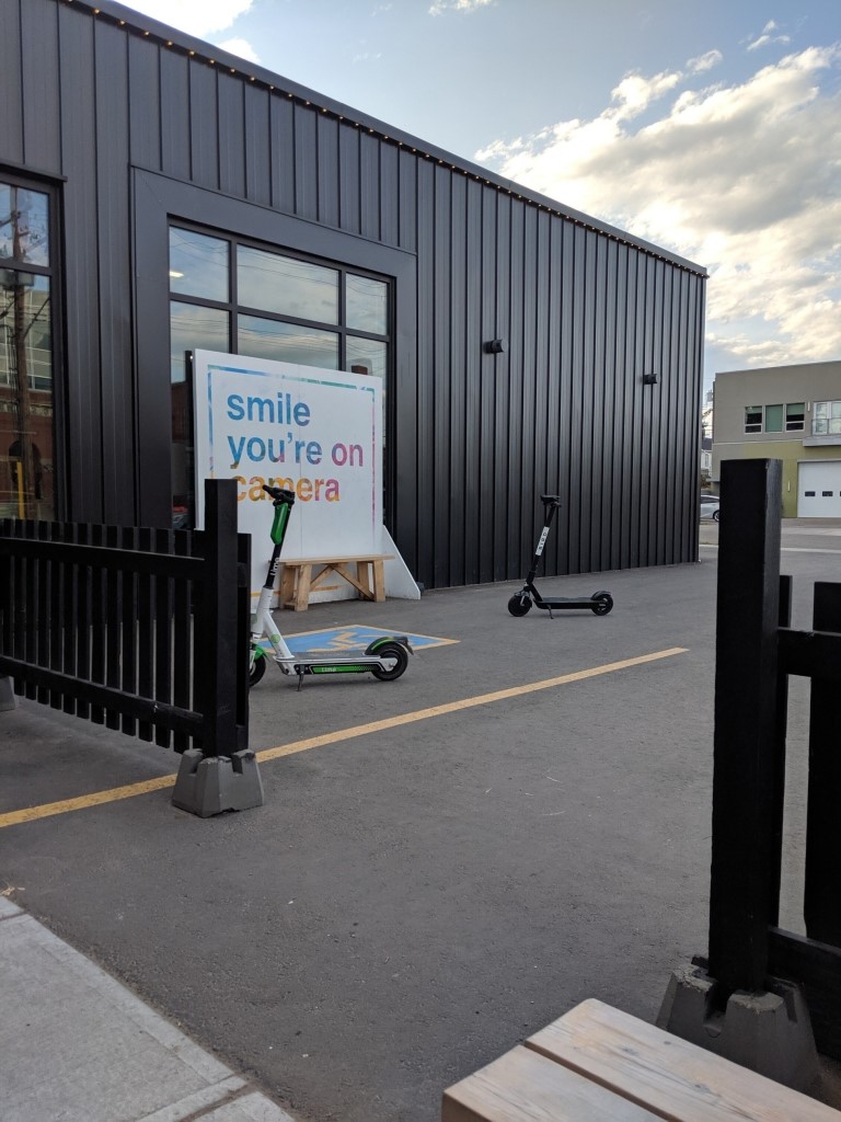 Two e-scooters sit side-by-side on a sidewalk outside a business in Edmonton