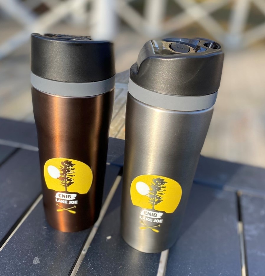 Bronze and charcoal coloured stainless steel travel mugs, with black lids on a table at camp.