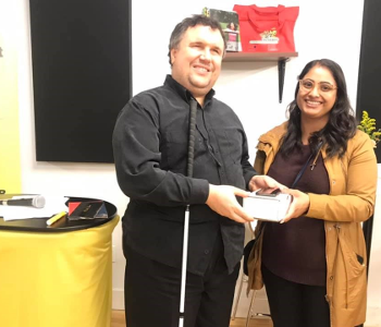 Aakruti Patel of West Groupe presents an iPhone to Sébastien Bolduc at the CNIB Montreal Hub.