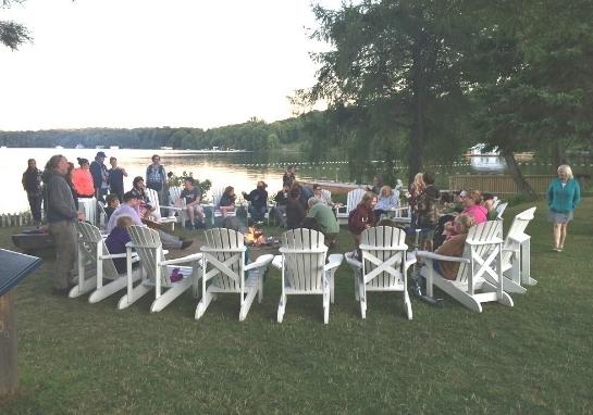 Guests sitting in Muskoka chairs around the campfire pit.