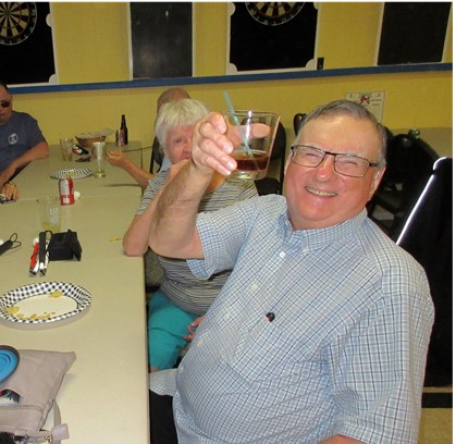 Wayne Laffin, assis à une table avec d'autres invités lors de la soirée de la Légion à MacTier, lève son verre avec un grand sourire. 