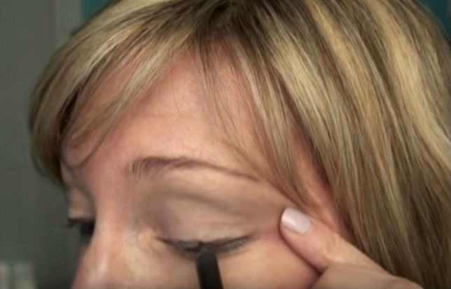 Femme utilisant un traceur pour les yeux  