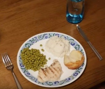 Image d’une assiette de nourriture avec une fourchette à sa gauche, un couteau à sa droite et un verre d’eau dans le coin supérieur droit