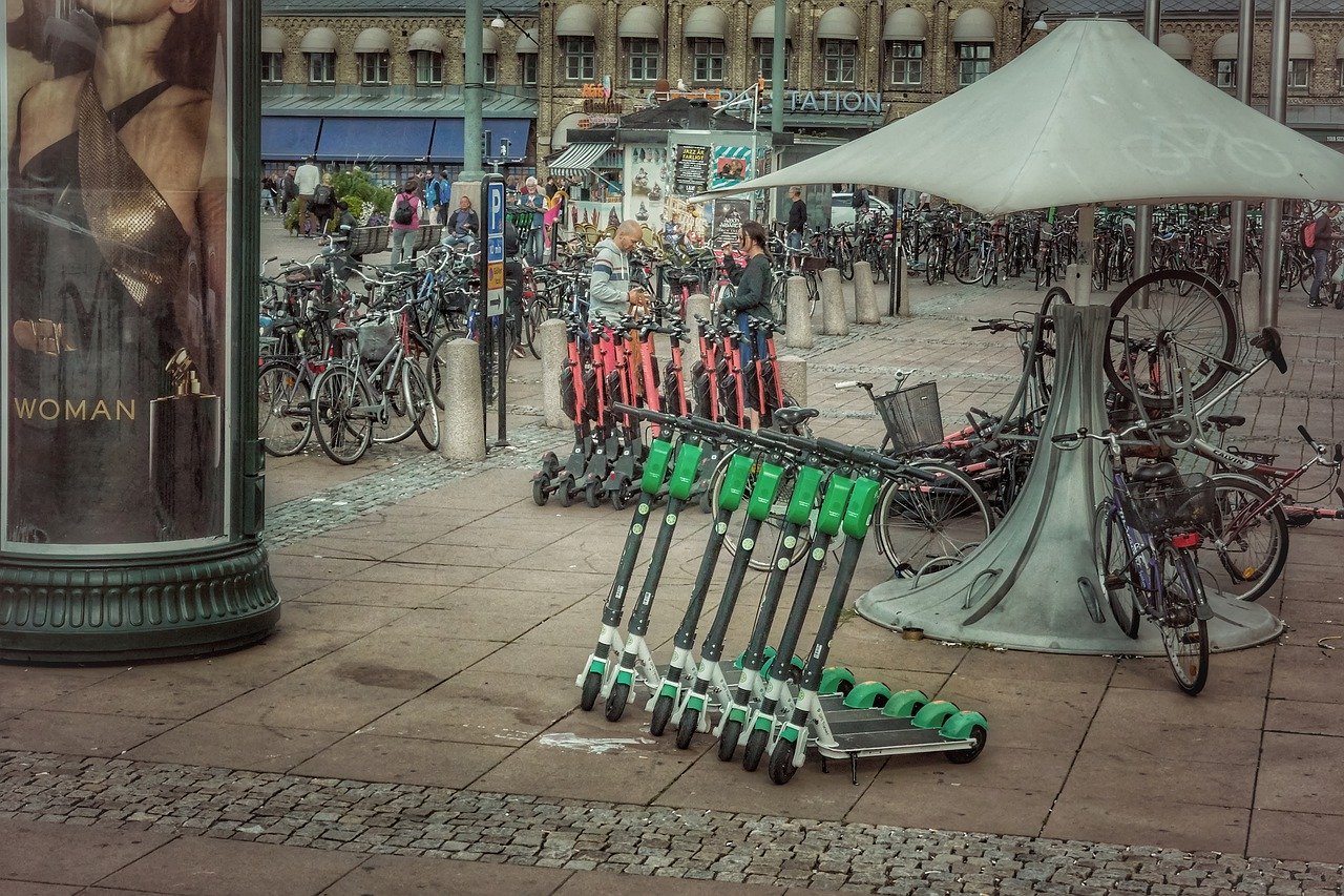 A city sidewalk with a row of electric scooters lined up on it.