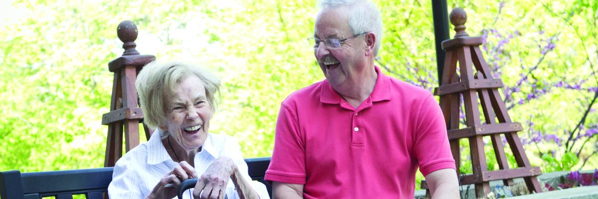 An older woman and man sitting on a bench laughing