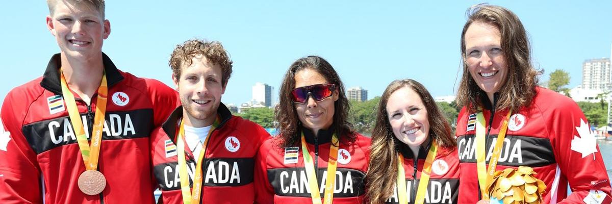 Victoria, along with two men and two women, wearing Team Canada Jackets and bronze medals.