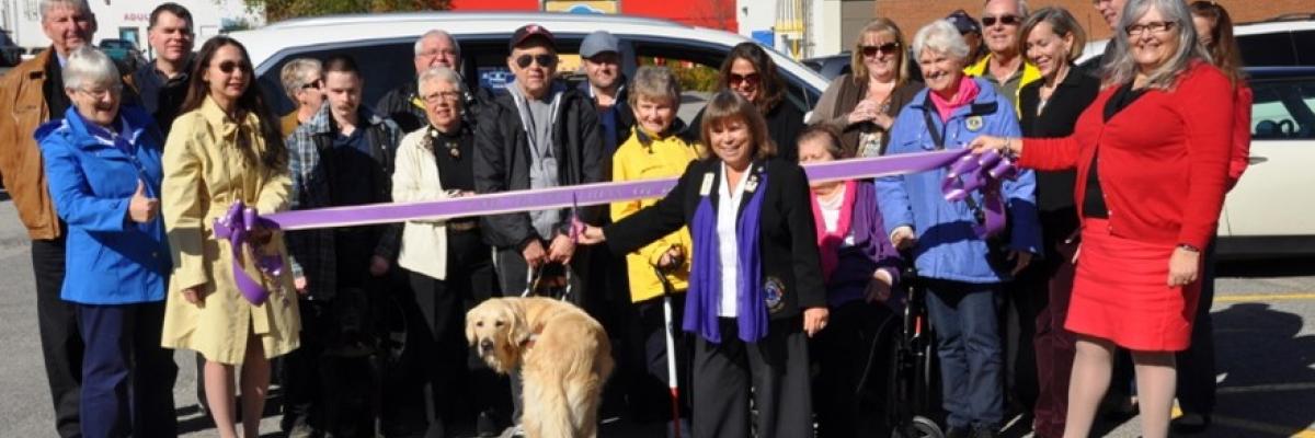 In 2015, Barb Ennis poses at a ribbon-cutting ceremony when she, as Lions District Governor for A12, purchased a brand new van to enhance client service. This van is now in service at CNIB Lake Joe!