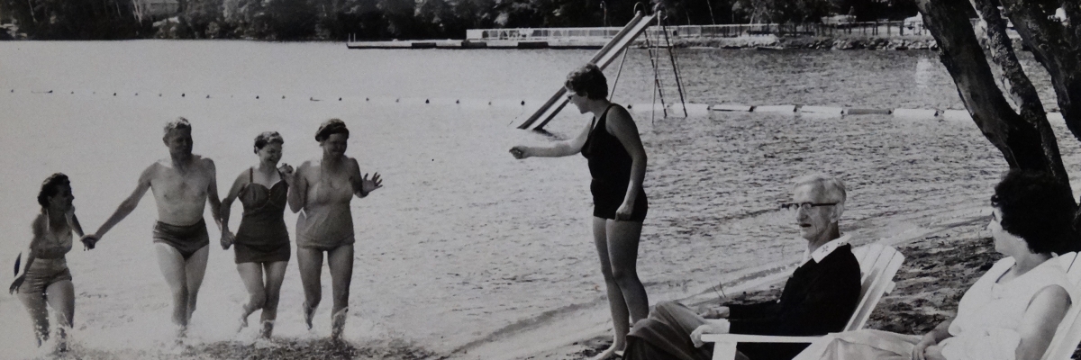 Ancienne photo en noir et blanc de campeurs sur les rives et la plage du lac en 1961
