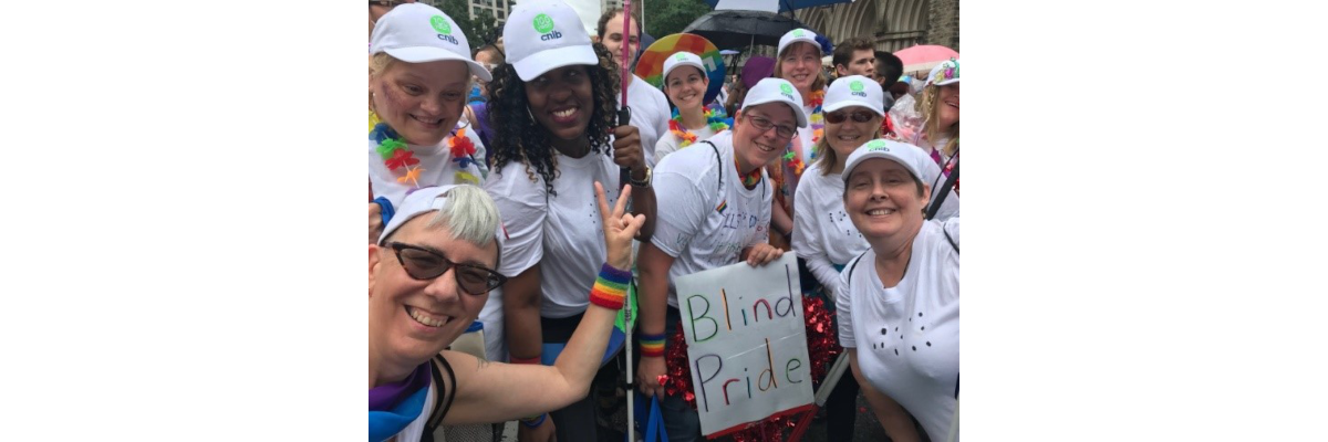CNIB participants, staff and volunteers sporting white t-shirts, baseball caps and smiles at the Toronto Pride parade