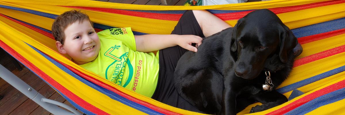 Ollie and Hope laying in a colourful hammock, cuddled up together and smiling