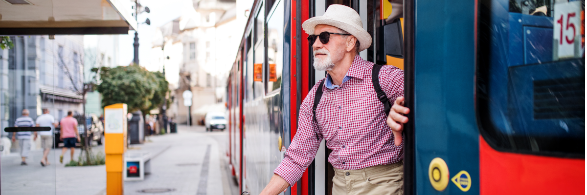 Un homme âgé utilisant une canne blanche quitte un autobus.