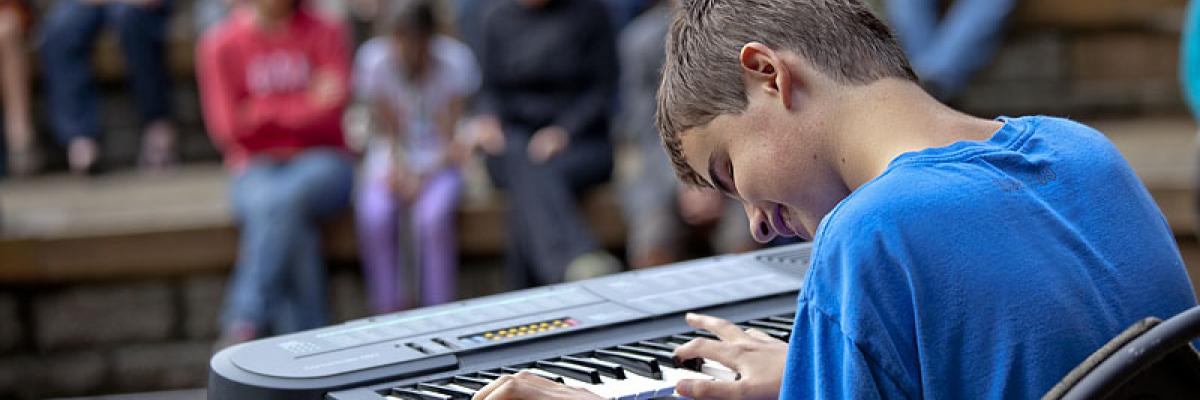 boy with sight loss playing keyboard for a crowd
