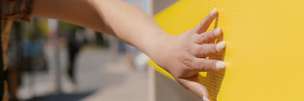 Une image d'une main tendant la main pour toucher un signe braille en jaune INCA