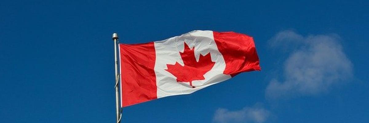 Un drapeau canadien flotte dans un ciel bleu et clair.