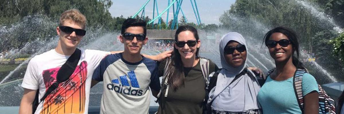 A group of four smiling teenagers and a volunteer pose for a photo at Canada's Wonderland. 