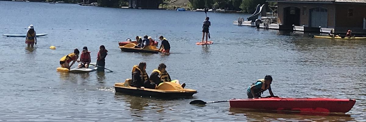 A group of kids participate in kayaking and paddle boating on the shores of CNIB Lake Joe.