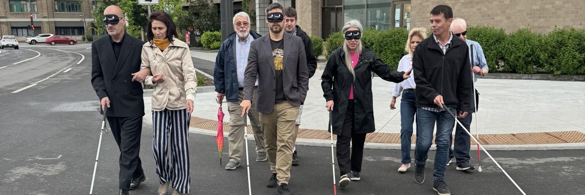 Claude les yeux bandés guidé par Valérie directrice d’INCA Québec, Pierre-Luc les yeux bandé guidé par Jean-Michel et un bénévole derrière lui, Maude guidée par David et René du RPHV 03-12 à l’arrière traversent la rue en direction de la caméra en balayant leur canne-blanche devant eux