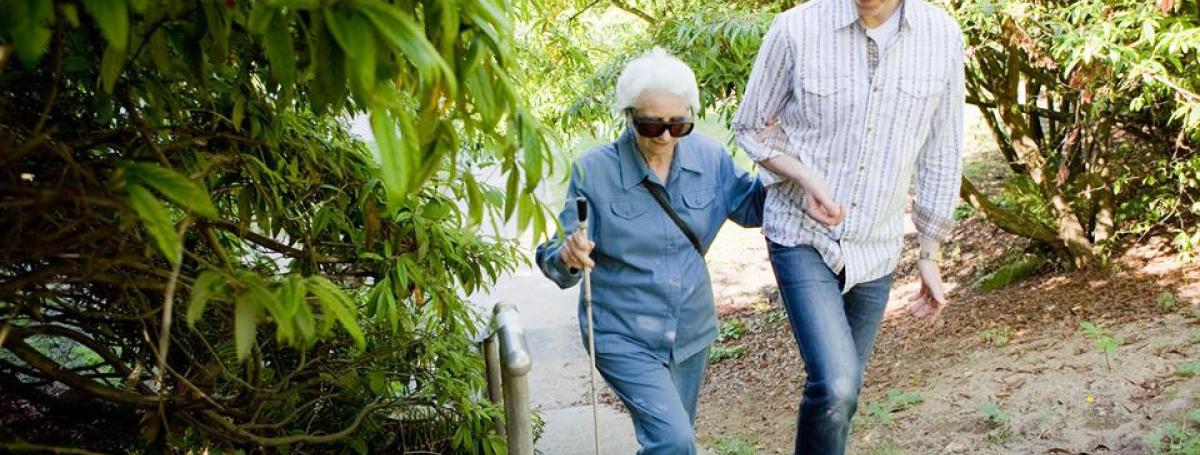 sighted guide walking with a woman using a white cane
