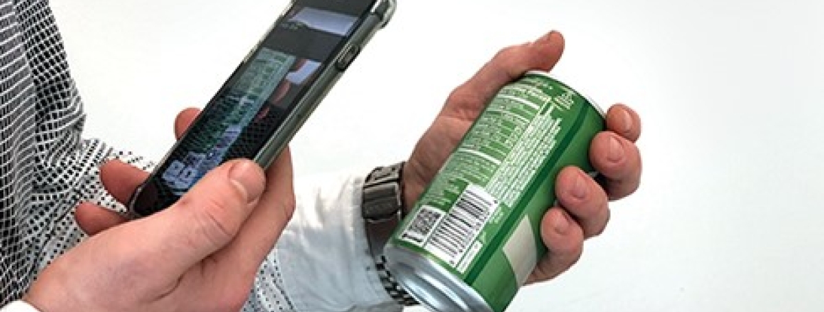 Une main tient un téléphone cellulaire devant le code-barre d'une canette