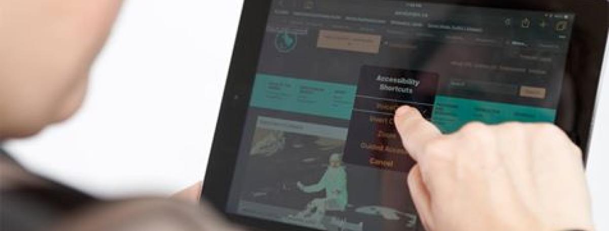 An over the shoulder shot of a woman tapping on an iPad.