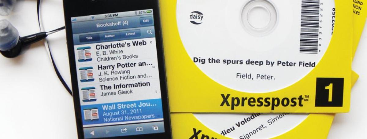 Photo of a Victor Stream displaying a reader’s bookshelf, next to DAISY books on CD.