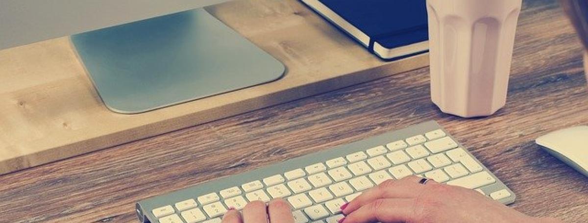 A woman's hands type on a computer keyboard.