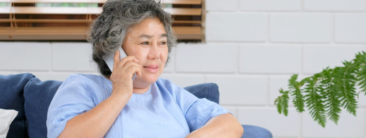 Une femme est assise sur un divan bleu et parle au téléphone.