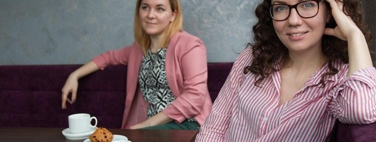 Two young women enjoy coffee at a cozy restaurant table.