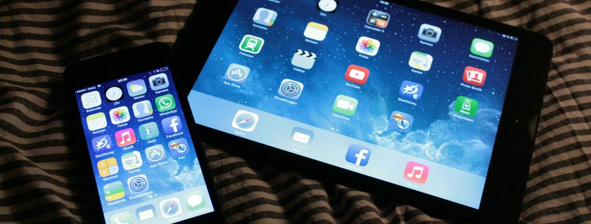 An iPhone and iPad sit side-by-side on a table top.