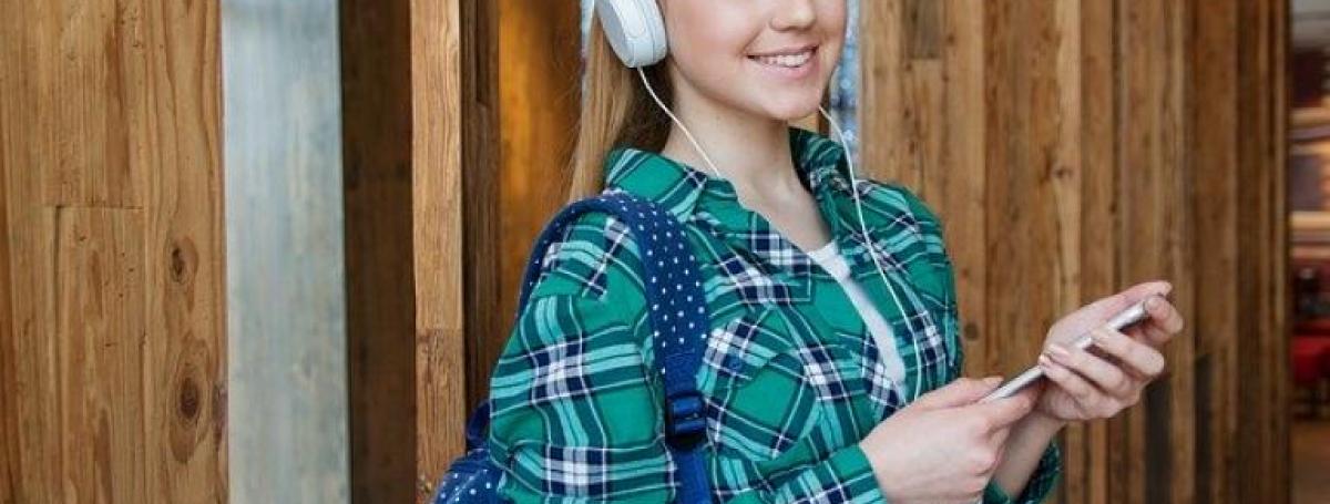 a girl with headphones on holding a cell phone