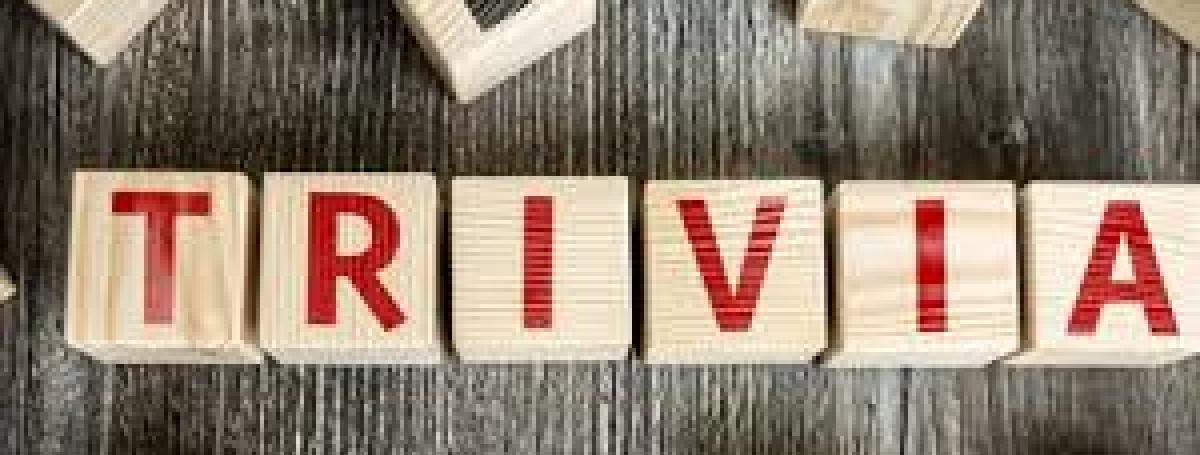 Wood blocks with red letters on them are laid on a table to spell "TRIVIA"