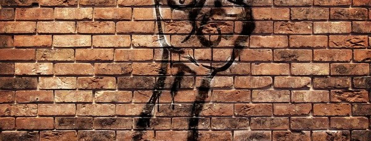 Artistic graffiti of a fist on a brick wall. Made with black spray paint.