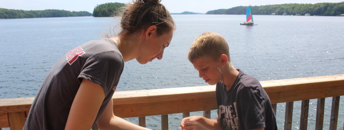 Female counsellor assists a young boy who has caught a fish.