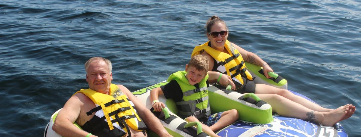 Man and woman sitting on a big inner tube with a young boy in-between.