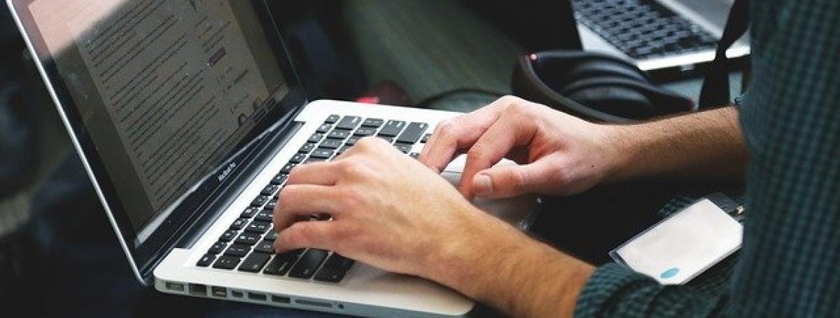 The silhouette of a mans hands typing on a laptop computer.